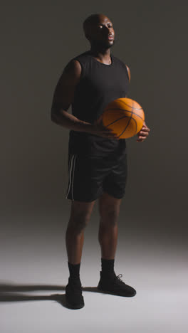 Vertical-Video-Full-Length-Studio-Shot-Of-Male-Basketball-Player-Dribbling-And-Bouncing-Ball-Against-White-Background